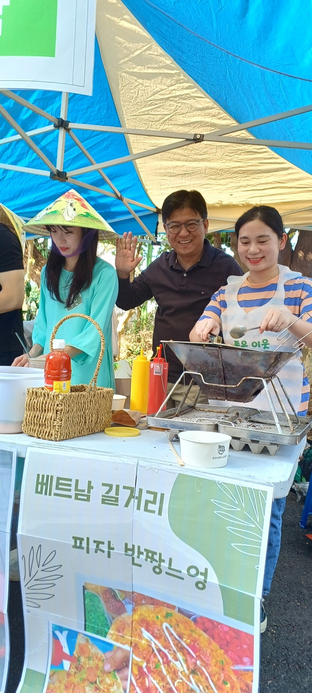 부산 해운대구 소명교회 노성현(가운데) 목사가 지난 4일 제2회 이웃과 더불어 함께하는 ‘더함축제’에 참가해 ‘체험마켓’에서 베트남 프엉(오른쪽)씨가 만드는 베트남 길거리음식 ‘반짱느엉’을 맛본 뒤 손을 들어 보이고 있다.